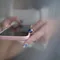 Close-up of hands with deep blue nail art holding a pink-cased smartphone.