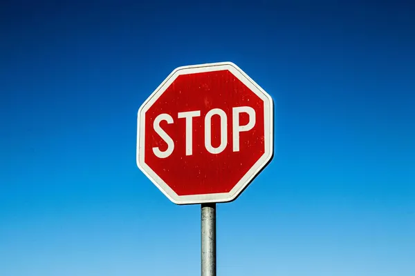Rotes Stoppschild vor klarem blauem Himmel