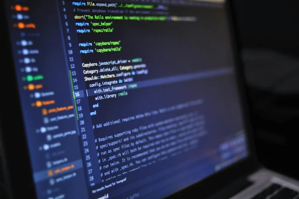 Laptop-Bildschirm leuchtet in einem dunklen Raum und zeigt Codezeilen